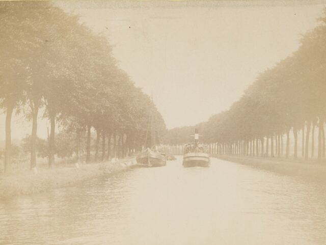 Oude foto van een binnenschip en een stoomschip op een kanaal met bomenrijen